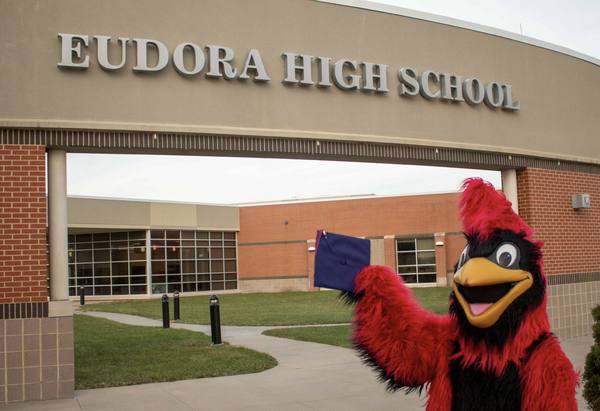 The Eudora Cardinals mascot waving a graduation cap in front of Eudora High School